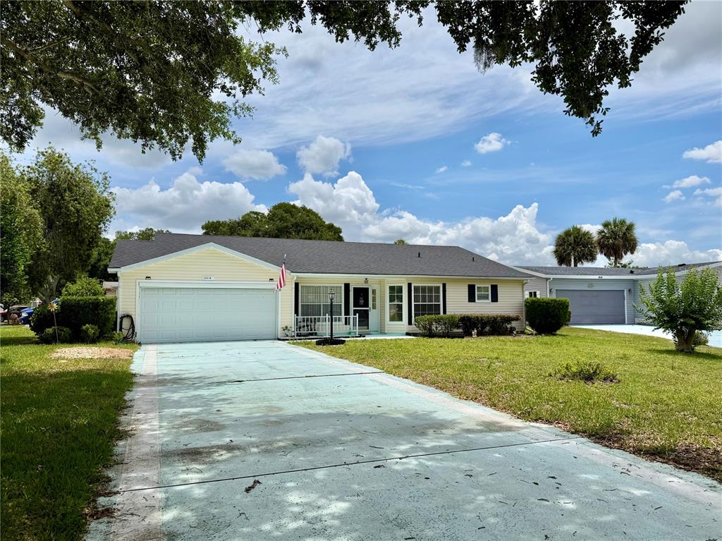 A single-story house with yellow siding, a white garage door, and a light-colored driveway — 25510 BELLE ALLIANCE, LEESBURG, FL