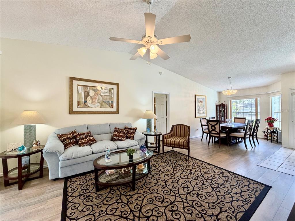 A living room and dining area with light-colored walls, wood-look flooring, and a ceiling fan — 25510 BELLE ALLIANCE, LEESBURG, FL