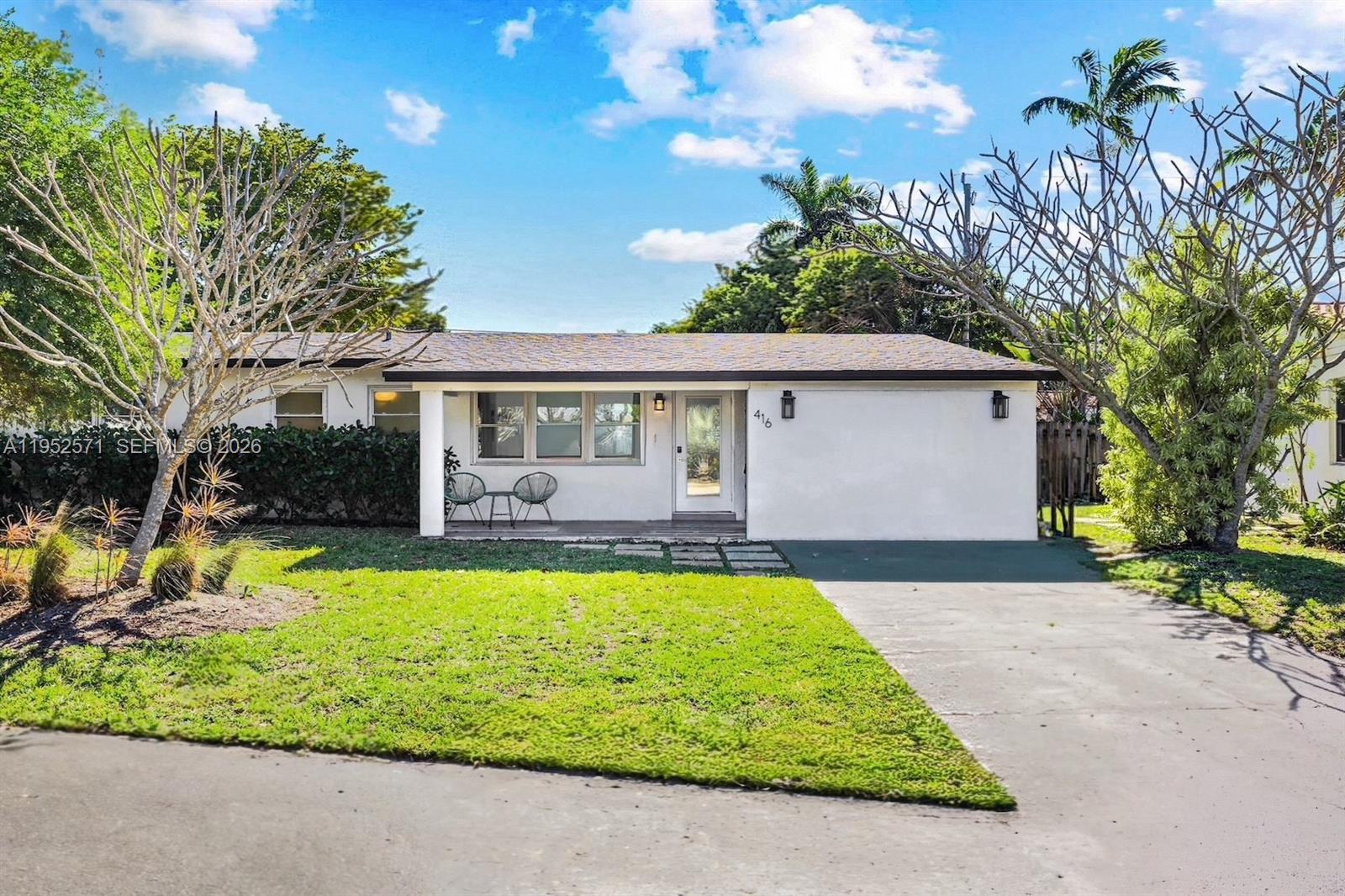 A single-story white house with a front porch, a paved driveway, and a grassy lawn — 416 NE 29th St, Wilton Manors FL 33334, WILTON MANORS, FL