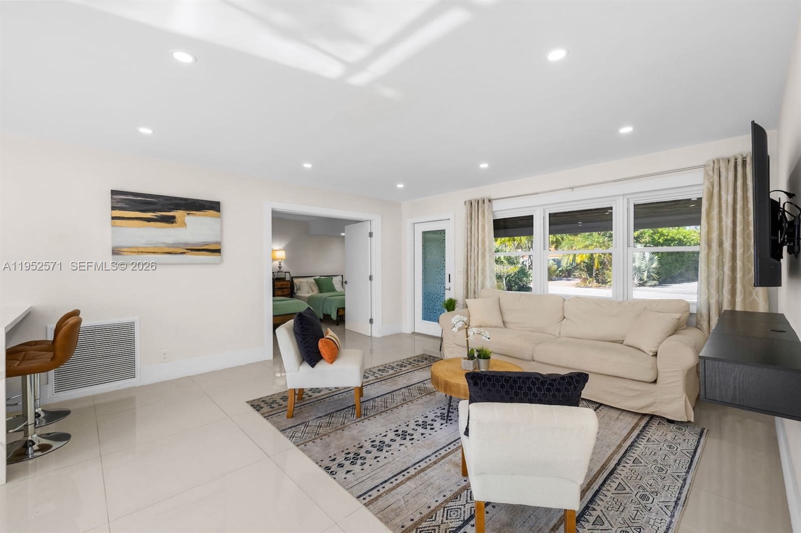 A living room features a beige sofa, two armchairs, a patterned rug, and tile flooring — 416 NE 29th St, Wilton Manors FL 33334, WILTON MANORS, FL