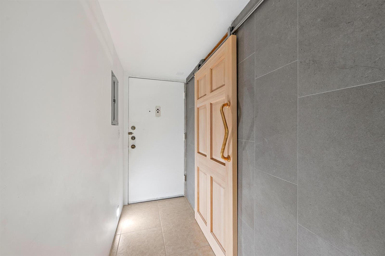 A hallway features a white entry door, a light wood sliding door, and gray tiled walls — 1516 S Lakeside Drive # 106, FL 33460, FL