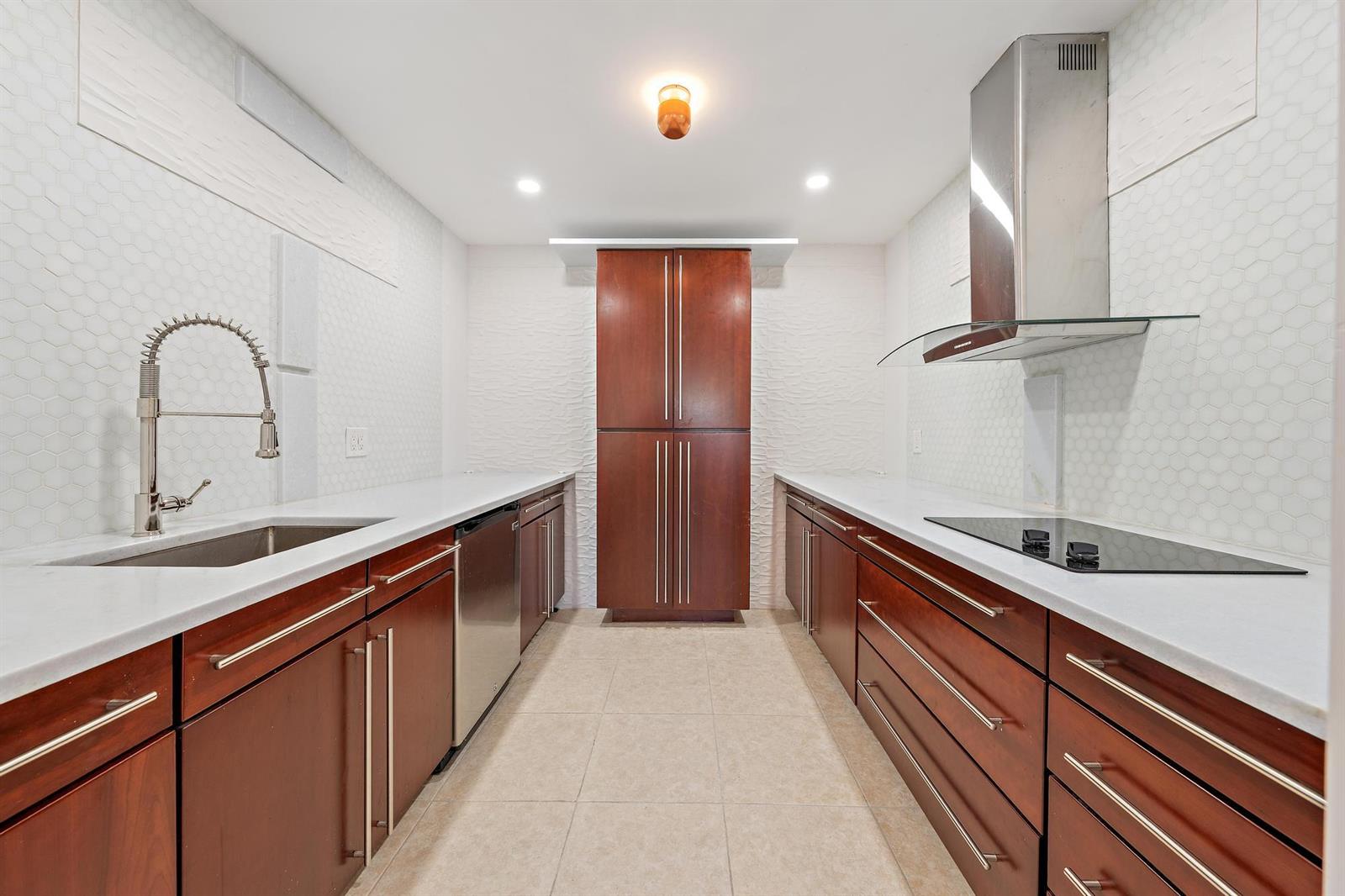 A galley kitchen features dark wood cabinets, white countertops, a stainless steel sink, and appliances — 1516 S Lakeside Drive # 106, FL 33460, FL