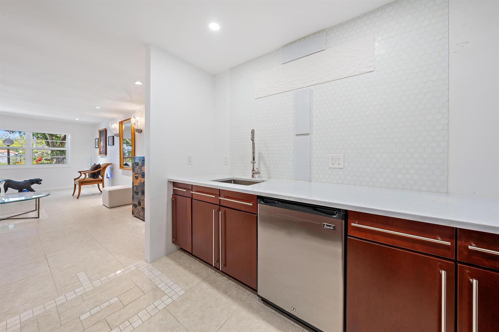 A wet bar with dark wood cabinets, white countertops, and a white hexagonal tile backsplash — 1516 S Lakeside Drive # 106, FL 33460, FL