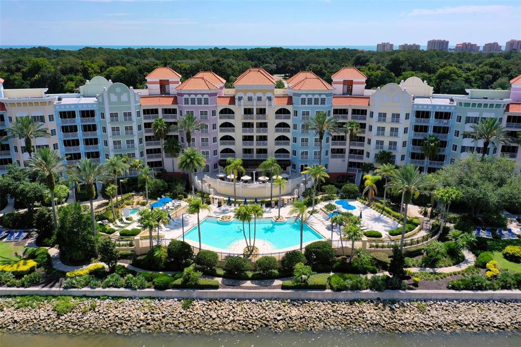 An aerial view of a multi-story colorful resort building with a central swimming pool — 237 and 239 YACHT HARBOR DR, PALM COAST, FL
