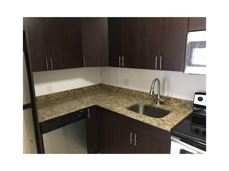 A kitchen features dark wood cabinets, granite countertops, a stainless steel sink, and modern appliances — 4003 N University Drive # 107, Sunrise FL 33351, SUNRISE, FL