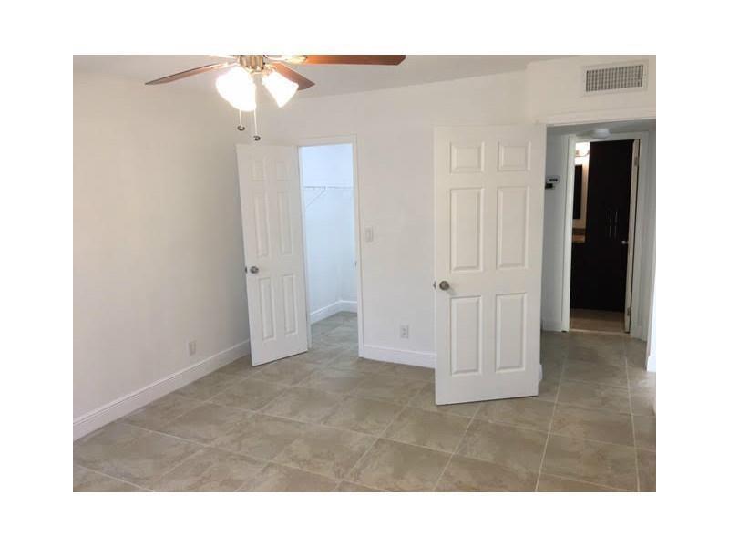 A bedroom features light-colored tile flooring, a ceiling fan, and two white interior doors — 4003 N University Drive # 107, Sunrise FL 33351, SUNRISE, FL