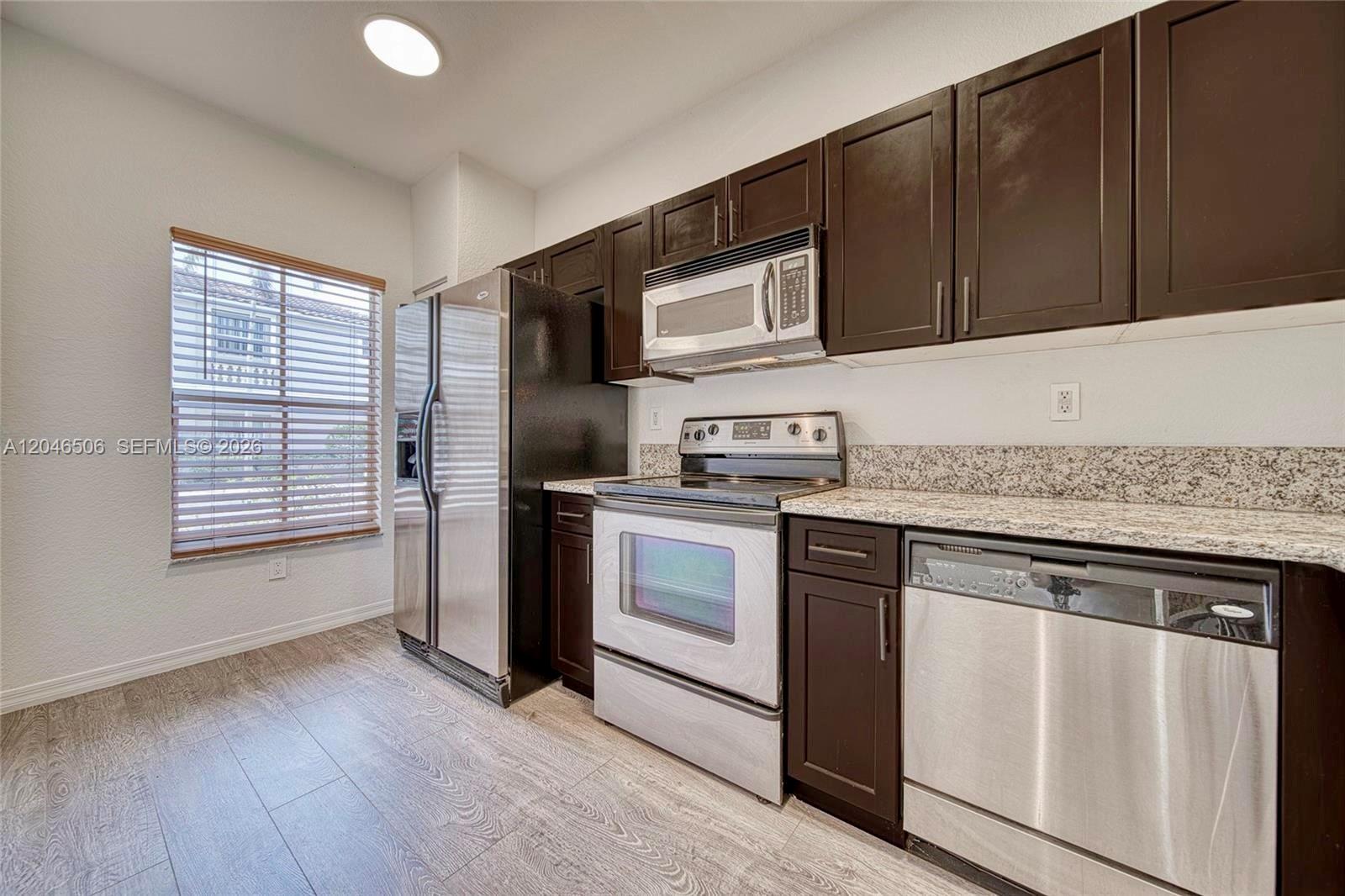 A kitchen features dark wood cabinets, stainless steel appliances, and granite countertops — 14033 SW 49th St # 6, Miramar FL 33027, MIRAMAR, FL
