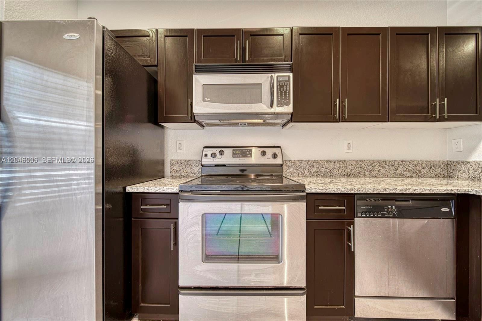 A kitchen features dark wood cabinets, stainless steel appliances, and speckled granite countertops — 14033 SW 49th St # 6, Miramar FL 33027, MIRAMAR, FL