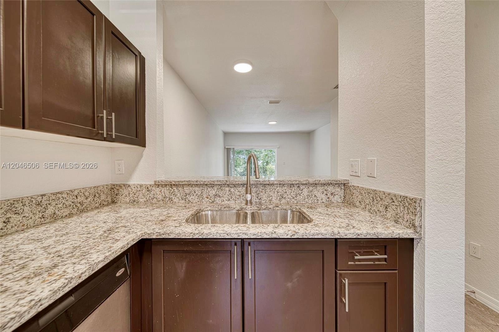A kitchen features dark wood cabinets, granite countertops, and a stainless steel double sink — 14033 SW 49th St # 6, Miramar FL 33027, MIRAMAR, FL
