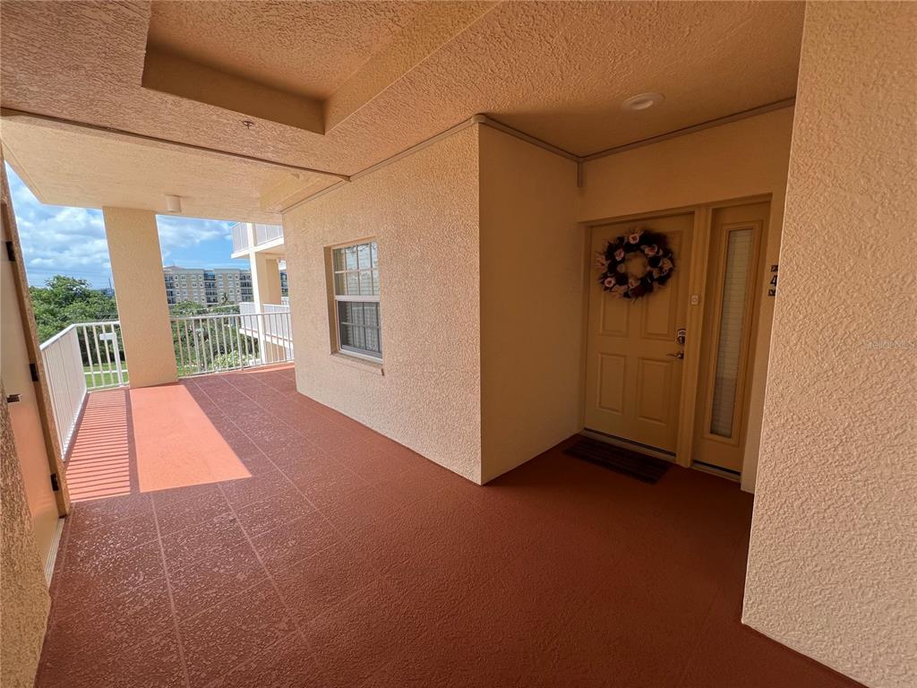 An outdoor covered entryway features a tan door with a wreath and orange flooring — 1188 N TAMIAMI TRAIL UNIT 403, SARASOTA, FL