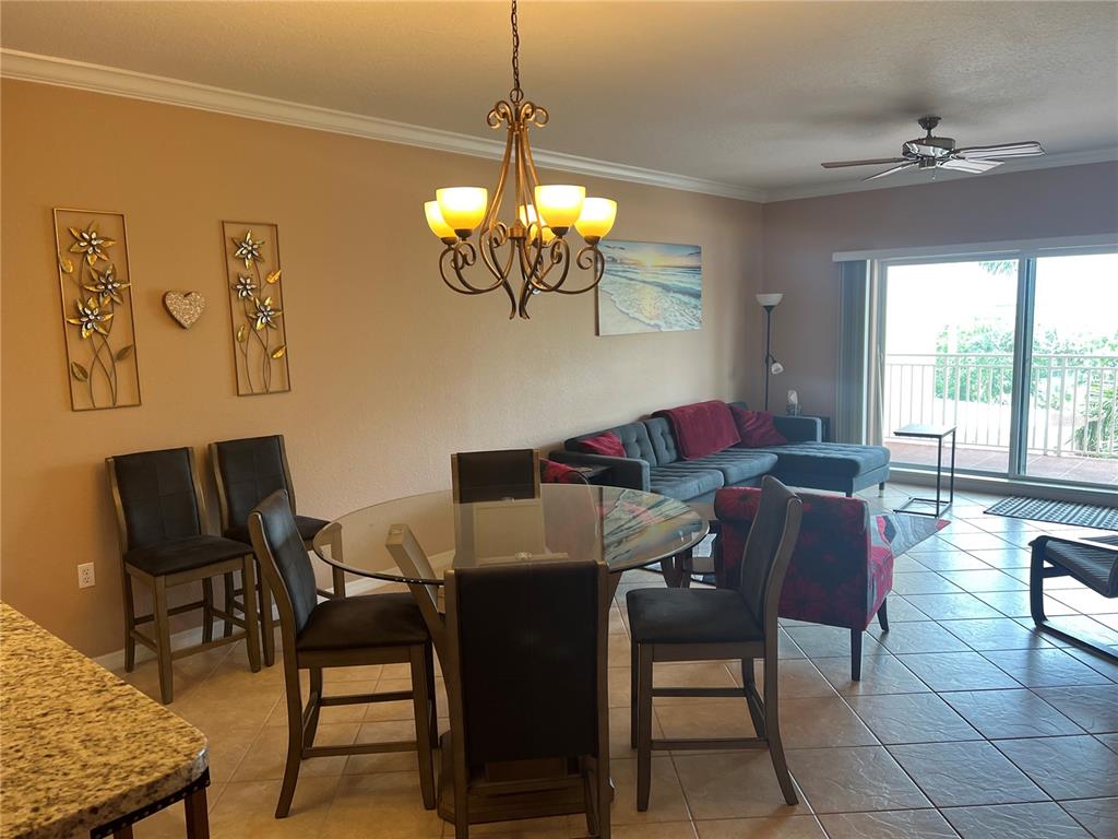 An open-concept living and dining area features a glass-top table, sectional sofa, and tile flooring — 1188 N TAMIAMI TRAIL UNIT 403, SARASOTA, FL