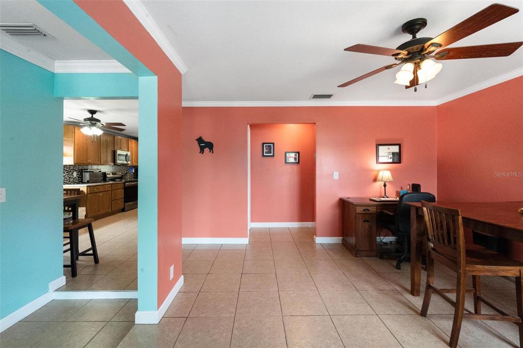 A room with coral walls, tile floors, a ceiling fan, and a view into the kitchen — 6250 5TH AVENUE S, ST PETERSBURG, FL