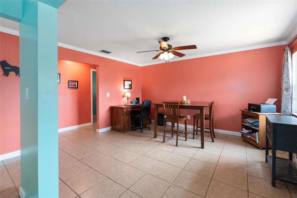 A dining area with coral walls, tile flooring, a wooden table, and a desk — 6250 5TH AVENUE S, ST PETERSBURG, FL