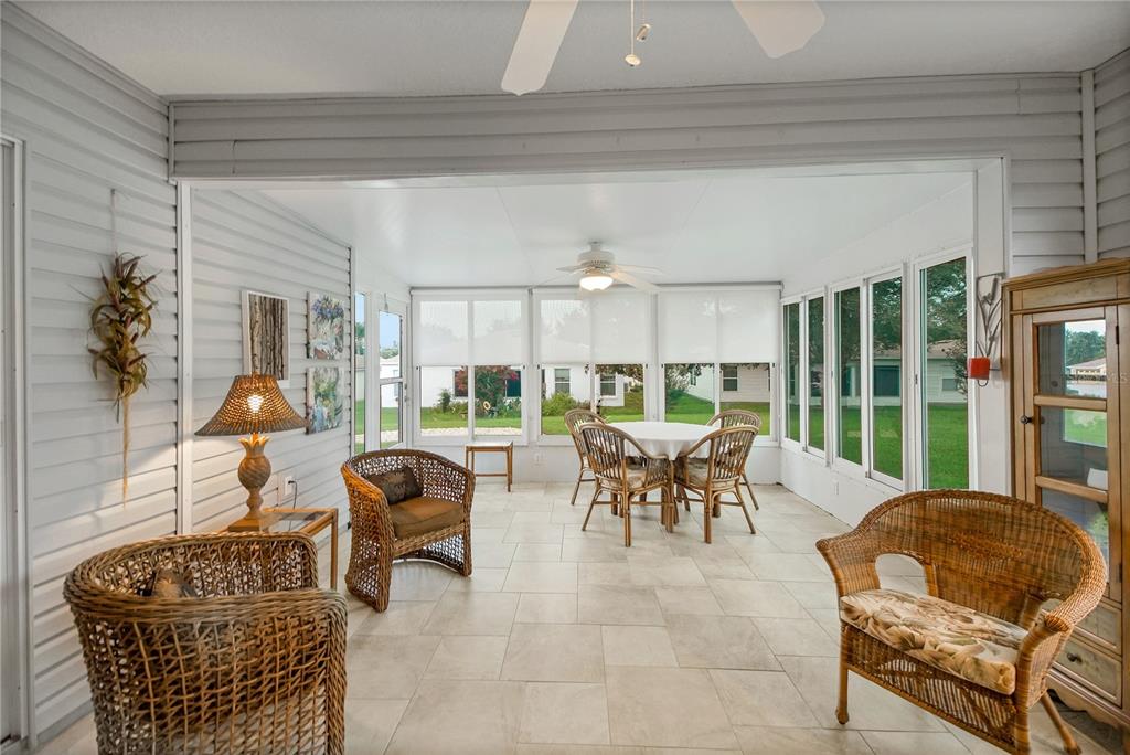 A sunroom features wicker furniture, a dining set, tile flooring, and large windows — 909 EAGLES LANDING, LEESBURG, FL