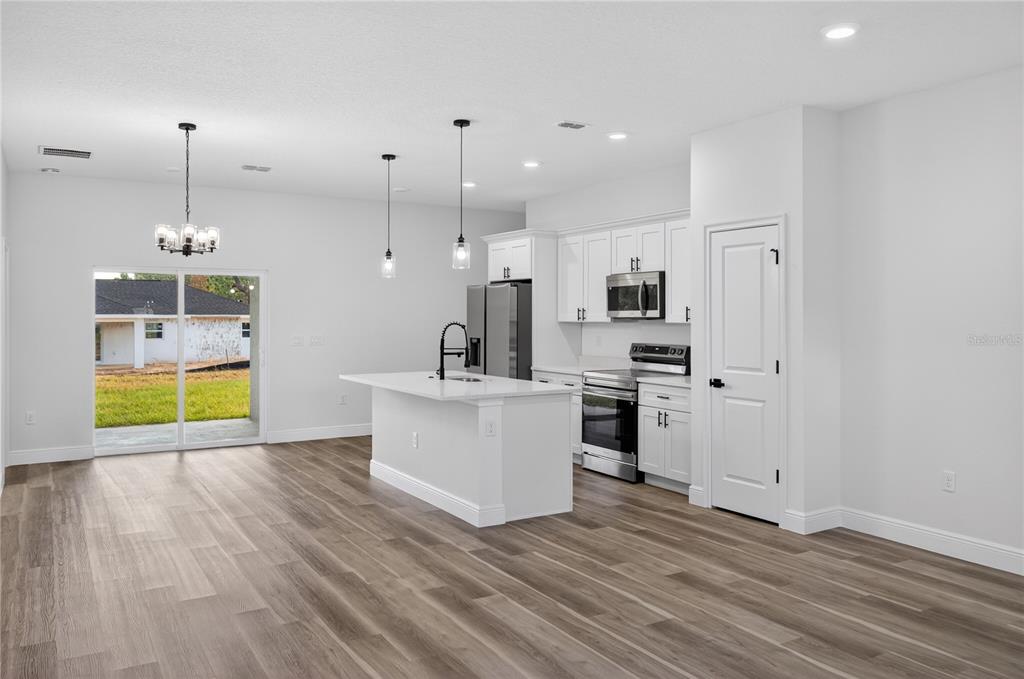 A modern kitchen with white cabinets, stainless steel appliances, and a central island with seating — 1852 W QUAKER LANE, CITRUS SPRINGS, FL