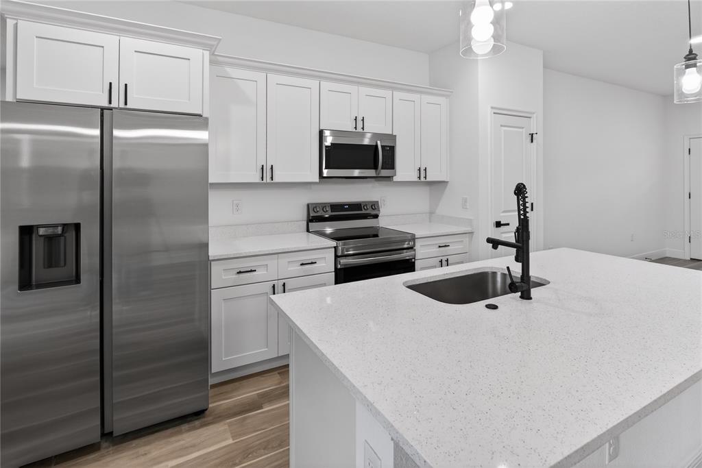A modern kitchen features white cabinets, stainless steel appliances, and a large quartz-topped island — 1852 W QUAKER LANE, CITRUS SPRINGS, FL