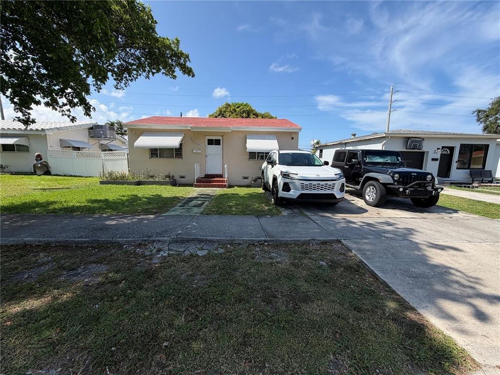 A single-story house with a red roof, white awnings, and two cars parked in front — 2447 ARTHUR STREET, HOLLYWOOD, FL