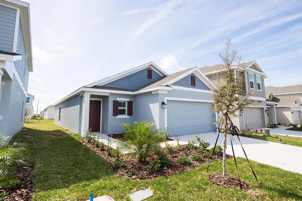 A single-story house with a blue-grey exterior, a two-car garage, and a front yard — 2165 AQUIFER LANE, DAVENPORT, FL