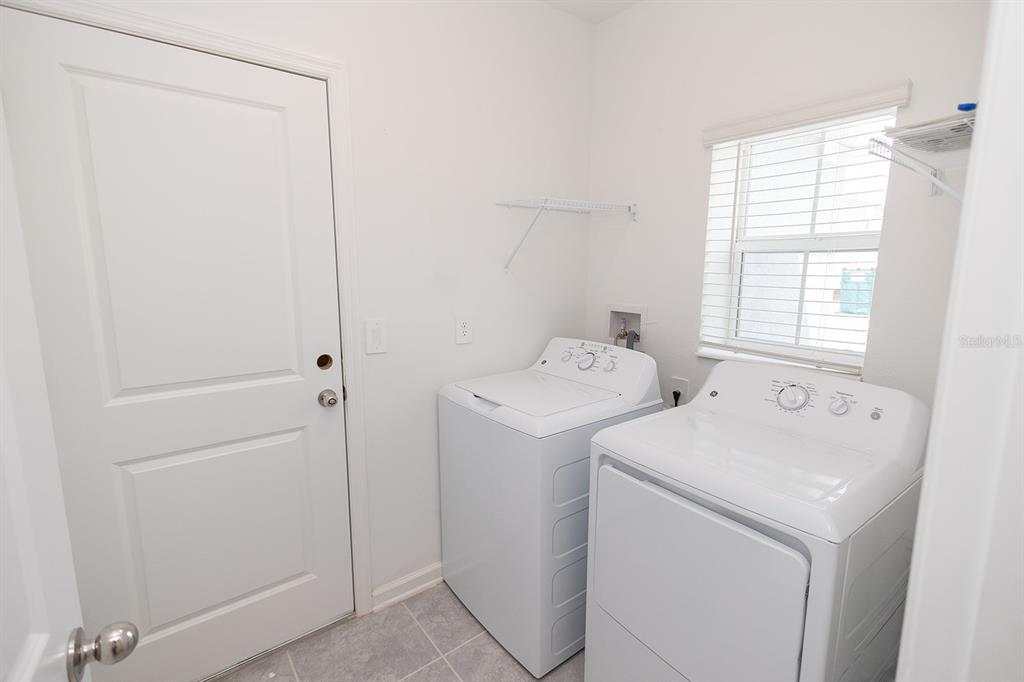 A laundry room features white appliances, a window with blinds, and a door — 2165 AQUIFER LANE, DAVENPORT, FL