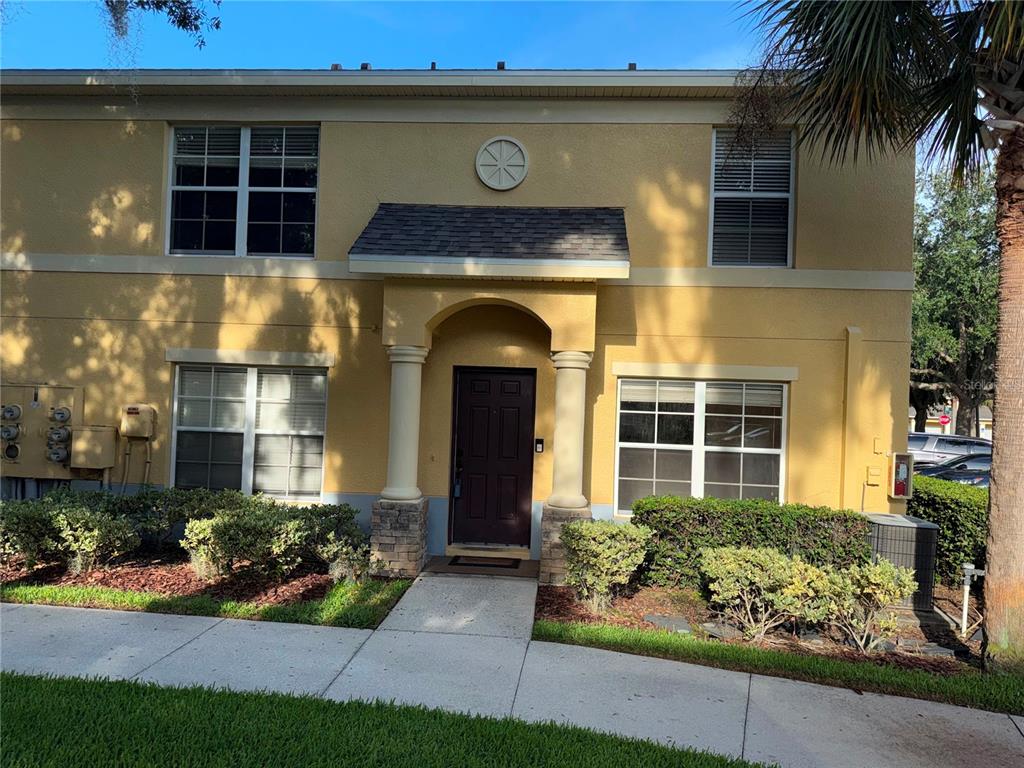 A two-story yellow stucco townhouse features a covered entryway with columns and a front door — 37603 DALIHA TERRACE, ZEPHYRHILLS, FL