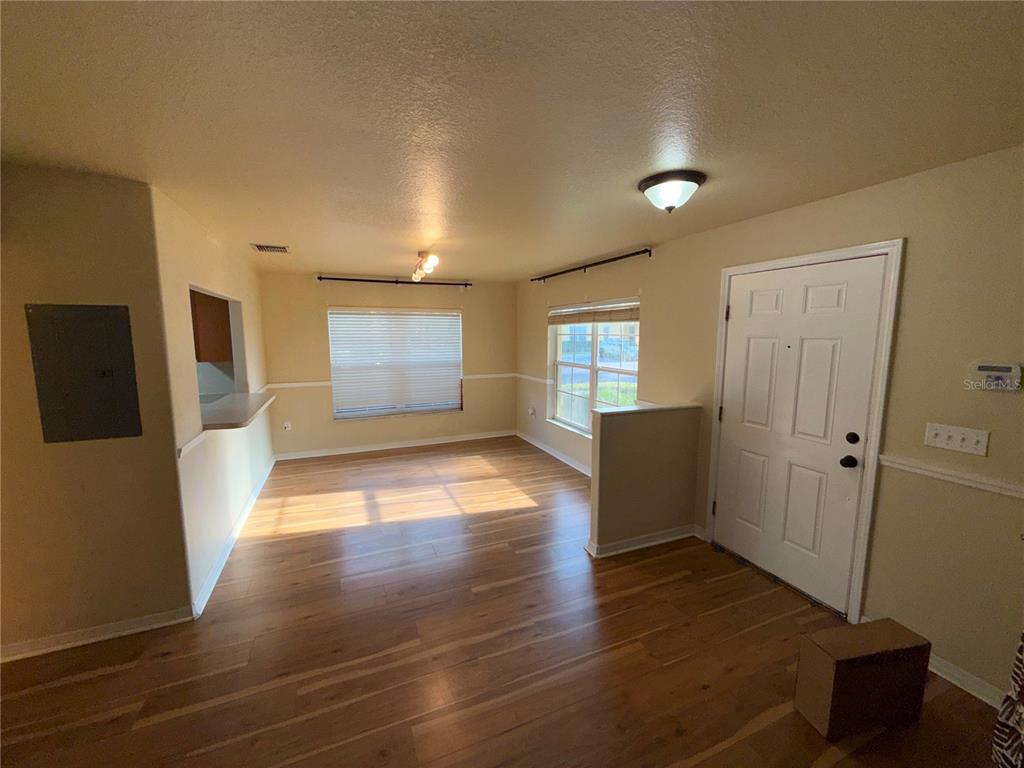 An empty room features wood-look flooring, a white front door, and two windows — 37603 DALIHA TERRACE, ZEPHYRHILLS, FL