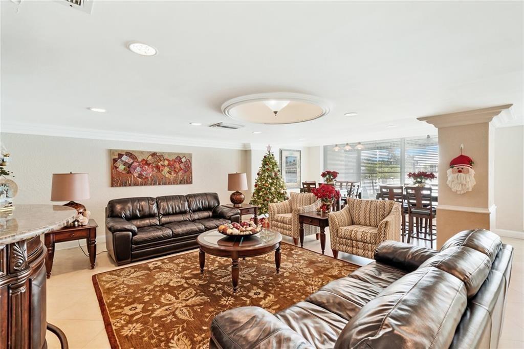 A living room features two leather sofas, patterned armchairs, a Christmas tree, and a rug — 303 N Riverside Drive # 4, Pompano Beach FL 33062, POMPANO BEACH, FL