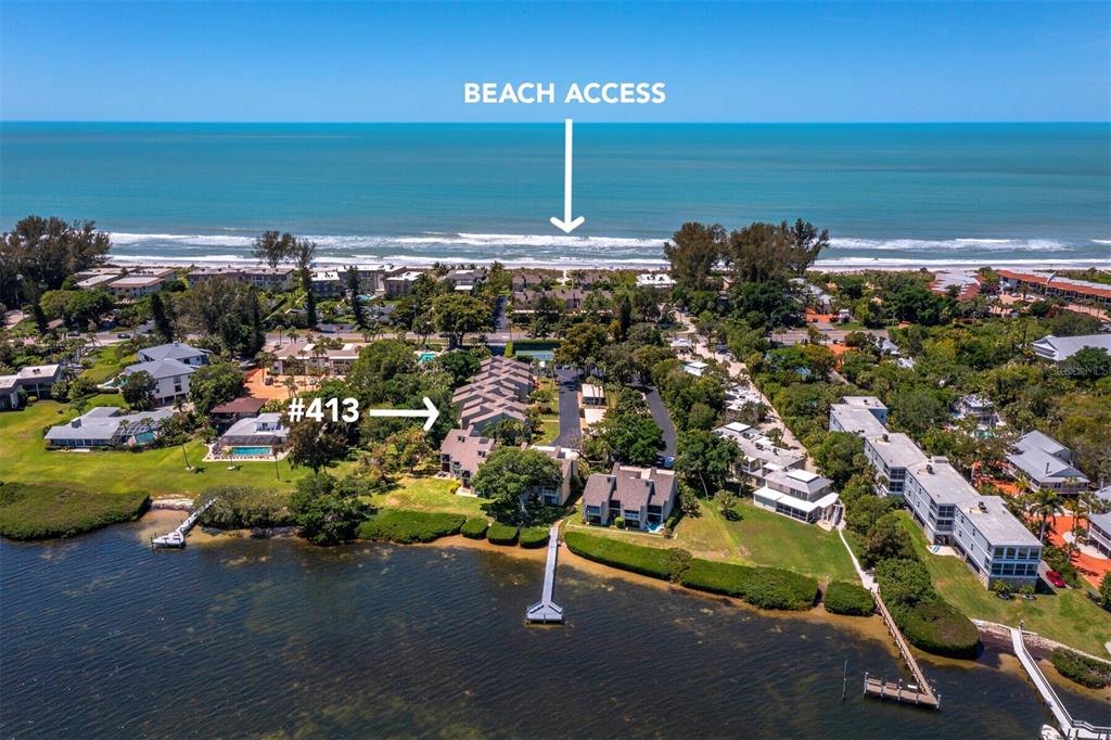 This aerial view shows a waterfront residential complex with a dock and beach access — 5260 GULF OF MEXICO DRIVE UNIT 413, LONGBOAT KEY, FL