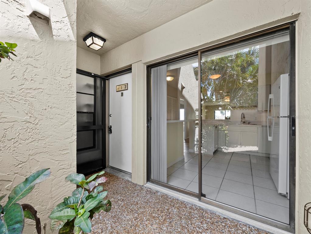 An exterior view shows a patio entrance with a sliding glass door and front door — 5260 GULF OF MEXICO DRIVE UNIT 413, LONGBOAT KEY, FL