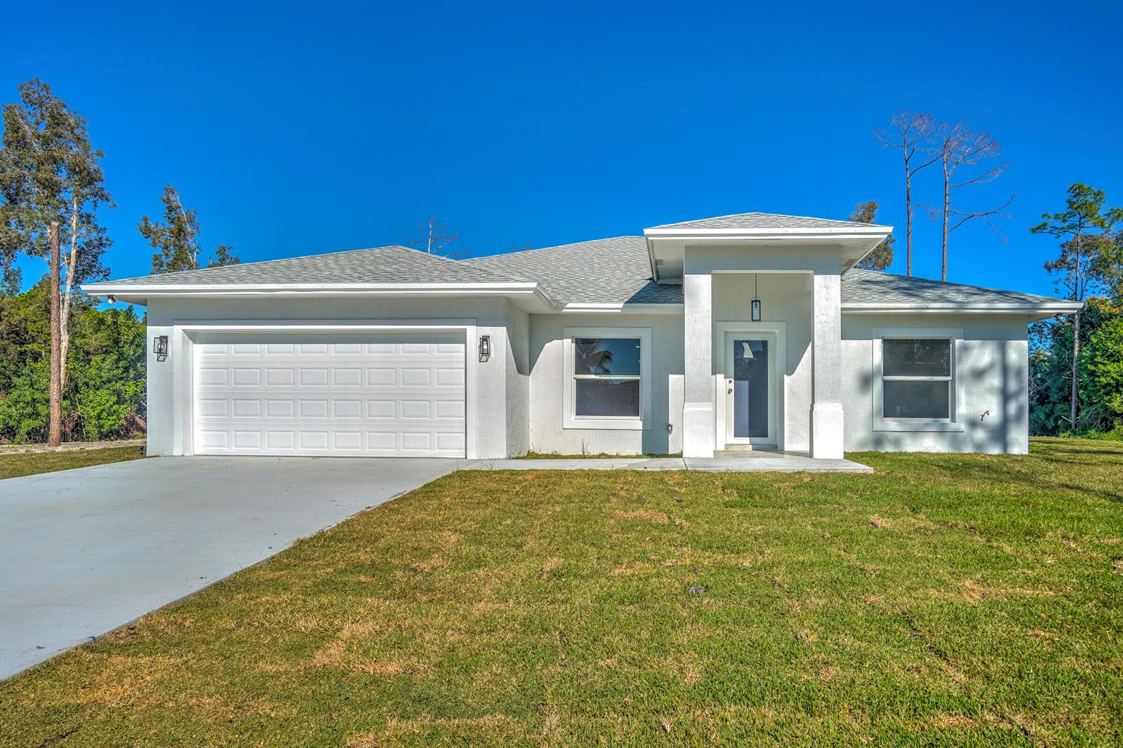 A single-story white stucco house with a two-car garage and a covered front entryway — 13875 63rd Lane N, FL 33470, FL