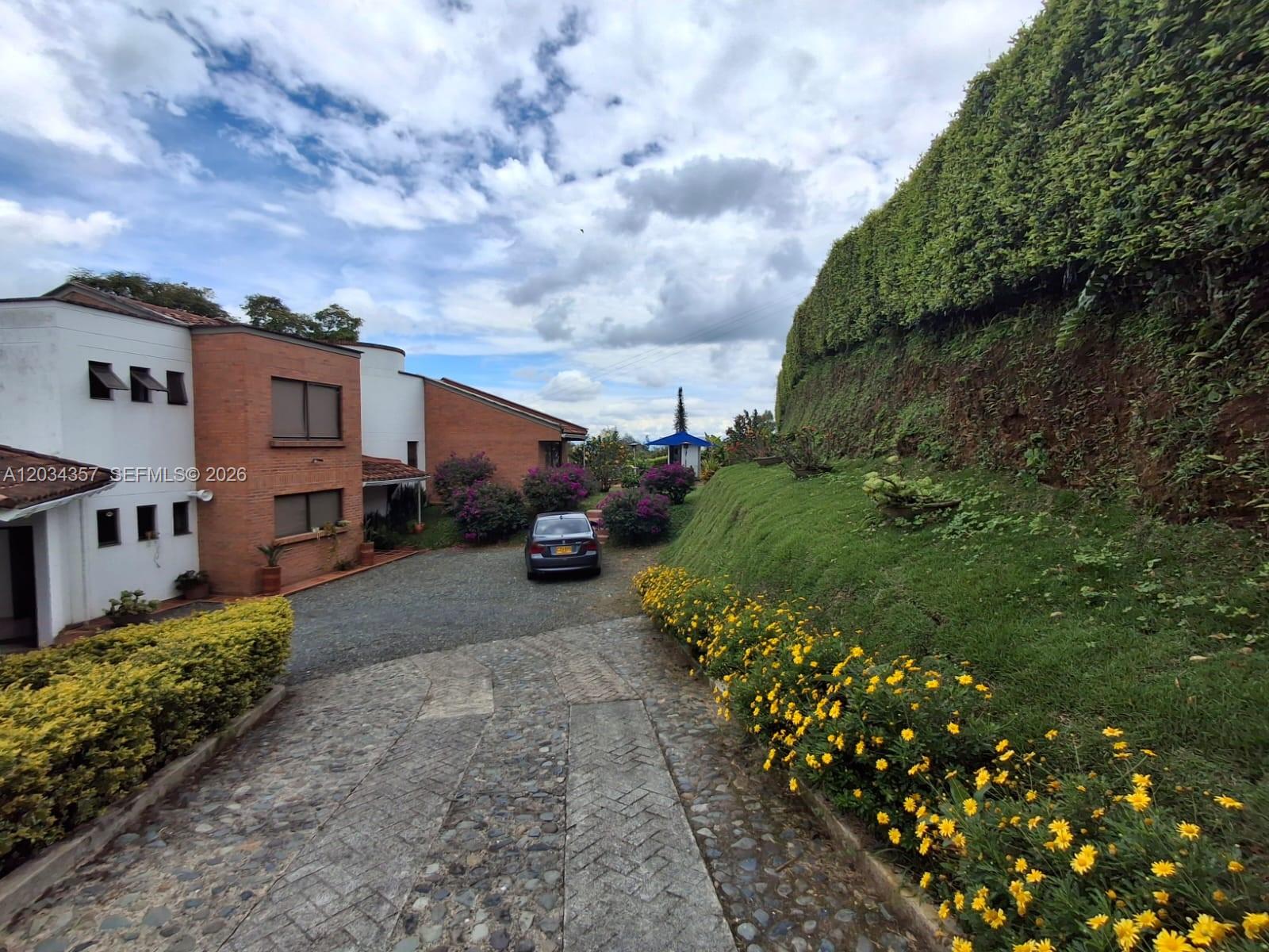 A paved driveway leads to a brick house with a large, landscaped grass embankment nearby — Casa Campestre Condominio Las Cabañas Casa 8, FL, FL