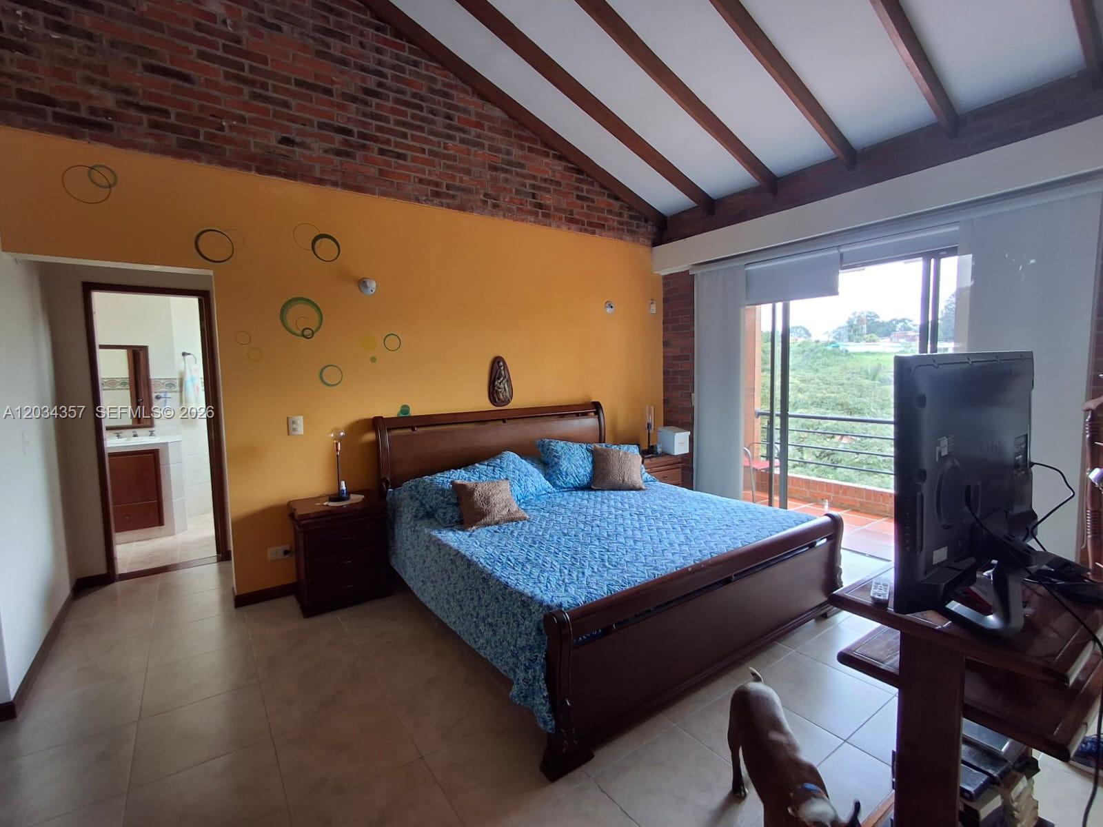 A bedroom features a brick wall, vaulted ceiling, orange paint, and a balcony with greenery — Casa Campestre Condominio Las Cabañas Casa 8, FL, FL