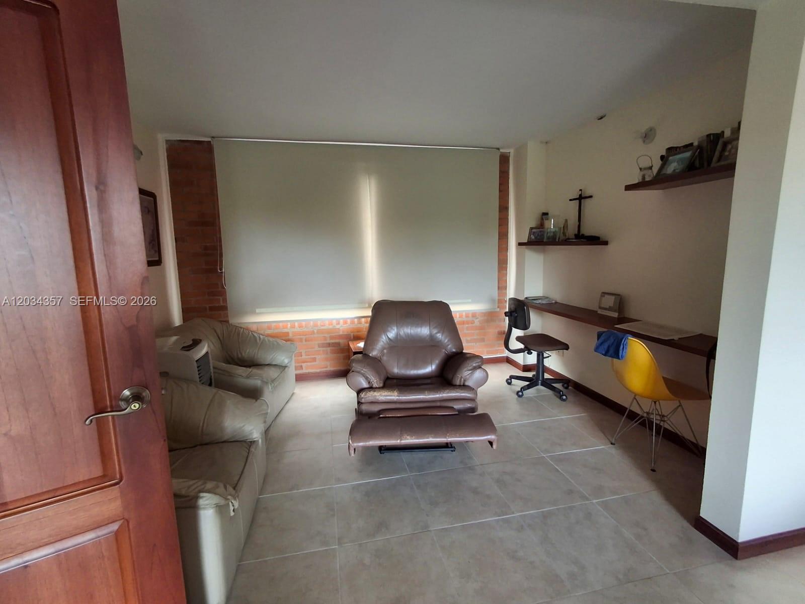A room features a brown recliner, a sofa, a desk with two chairs, and brick accents — Casa Campestre Condominio Las Cabañas Casa 8, FL, FL