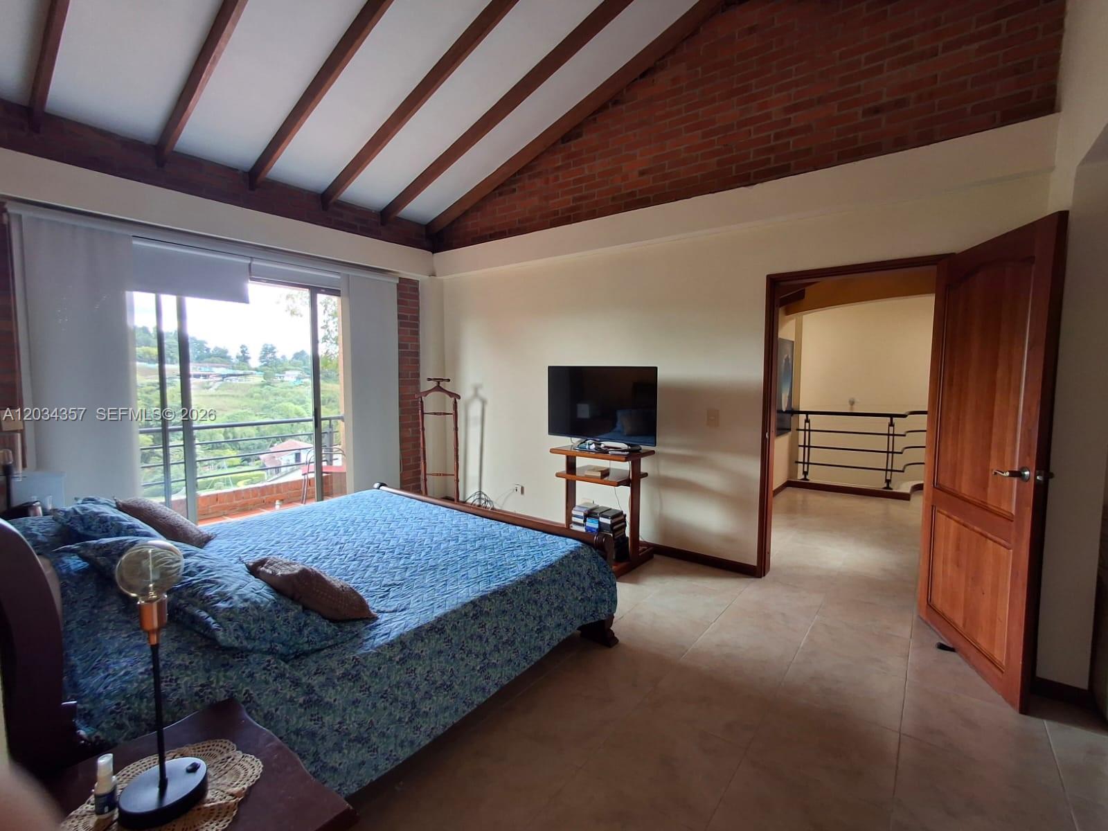 A bedroom features a vaulted brick ceiling, tile floors, a bed, and a balcony view — Casa Campestre Condominio Las Cabañas Casa 8, FL, FL