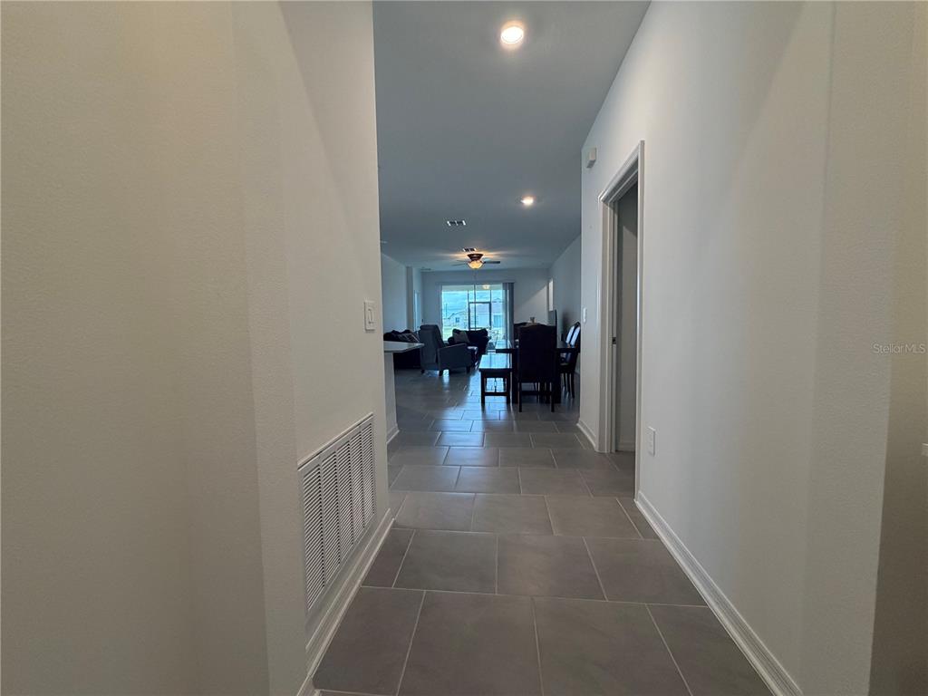 A hallway with gray tile flooring leads into an open-concept living and dining area — 652 GROVE STREET, WINTER HAVEN, FL