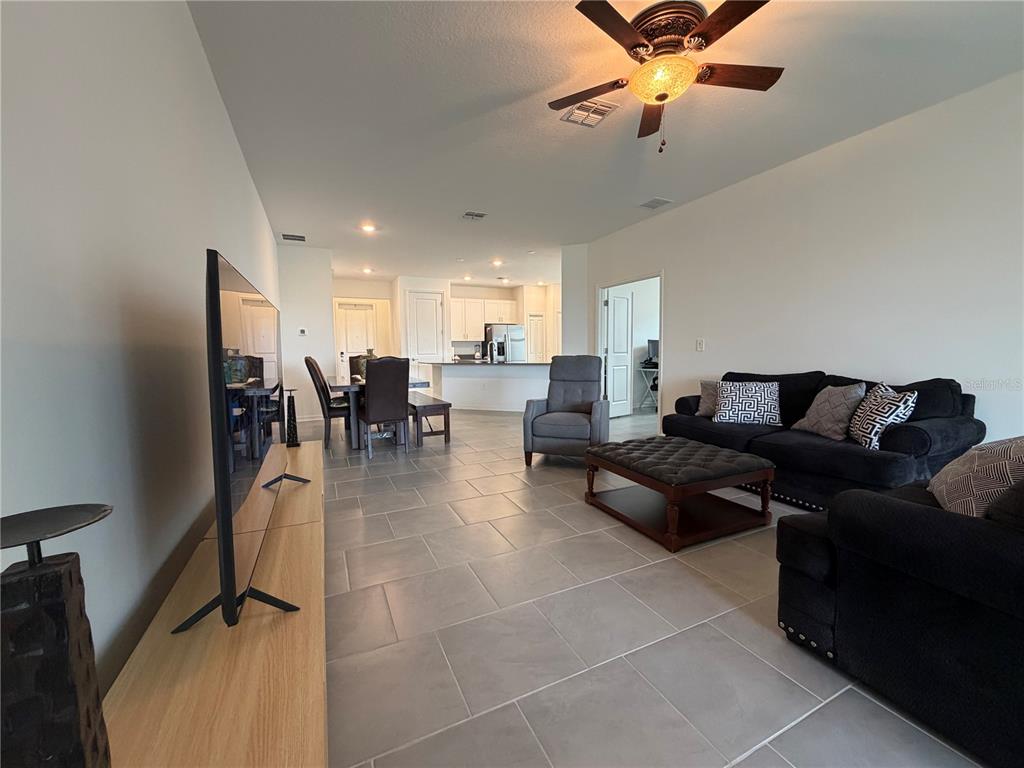A living room with tile flooring, a black sofa, and an open kitchen in the background — 652 GROVE STREET, WINTER HAVEN, FL