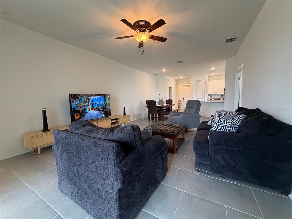 An open-concept living room features gray tile flooring, a ceiling fan, and a dining area — 652 GROVE STREET, WINTER HAVEN, FL