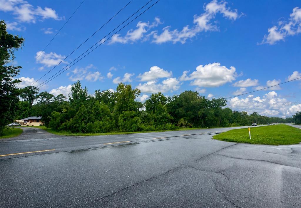 A paved road intersects with a gravel driveway in front of a wooded lot — 12002 HIGHWAY 441 S, MICANOPY, FL