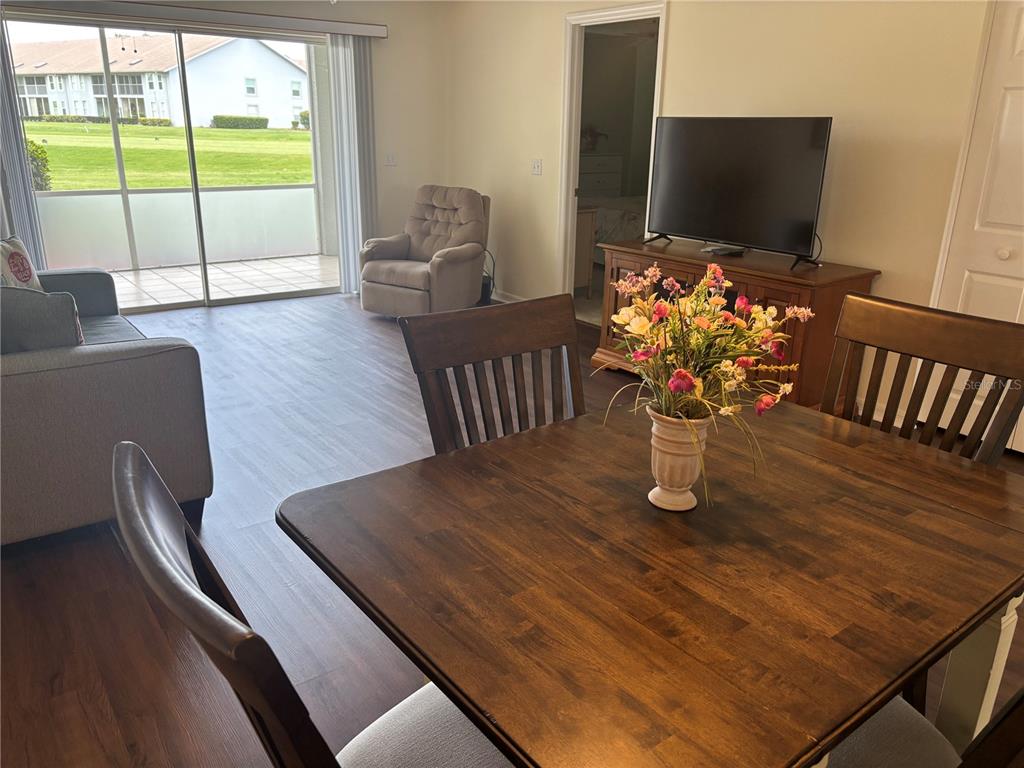 A dining area with a wooden table overlooks a living room and a screened patio — 6507 STONE RIVER ROAD UNIT 105, BRADENTON, FL