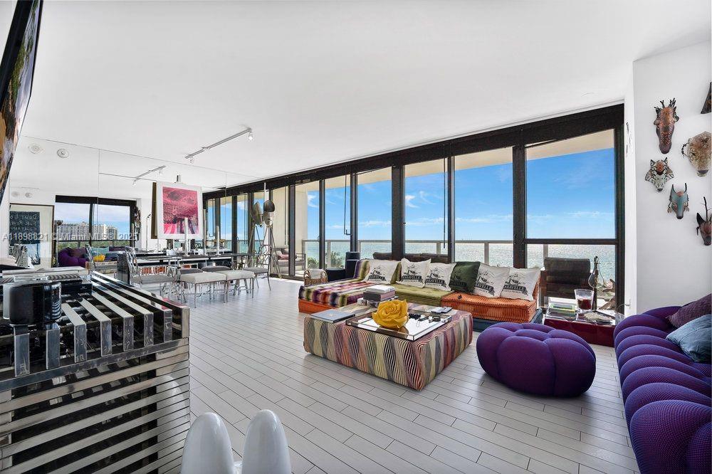 A spacious living room features floor-to-ceiling windows, light wood flooring, and vibrant modern furniture — 2201 Collins Ave # 628, Miami Beach FL 33139, MIAMI BEACH, FL