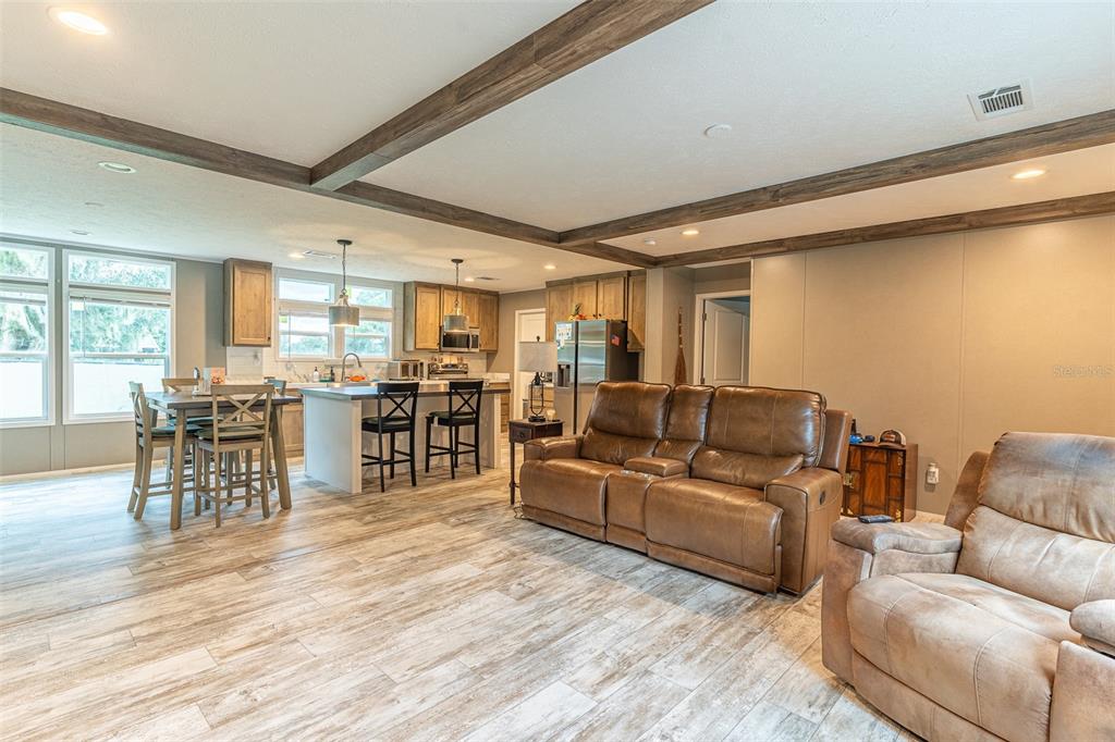 An open-concept living room and kitchen featuring wood-look tile flooring and exposed ceiling beams — 6668 CAIN STREET, MULBERRY, FL