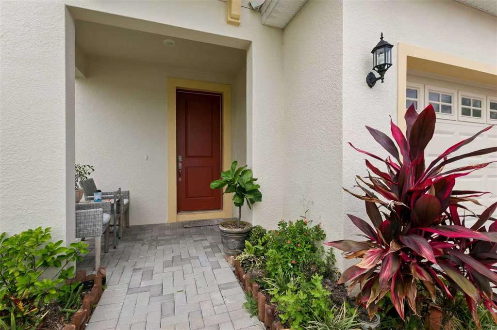 A paved walkway leads to a covered entryway with a red door and potted plant — 308 SHORE CRAB WAY, APOLLO BEACH, FL