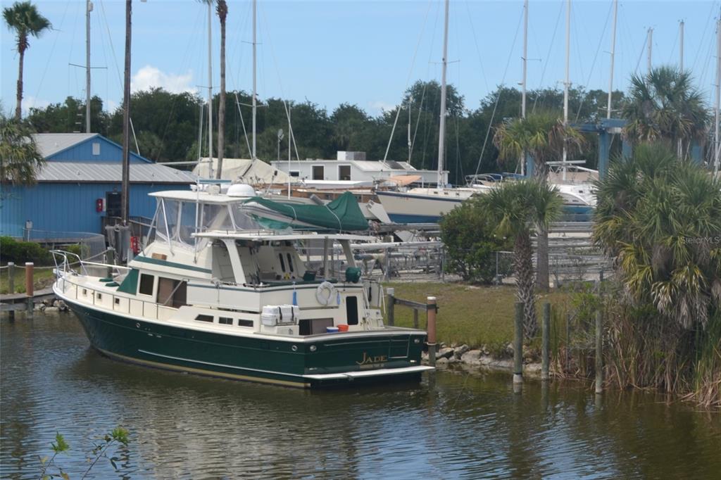 A green and white motorboat named Jade is docked in a canal near palm trees — 13570 STORM LAKE STREET, PORT CHARLOTTE, FL