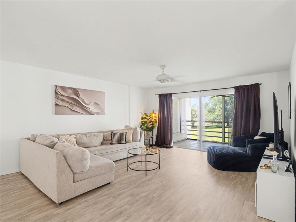 A living room features light wood-look flooring, a beige sectional, and a sliding glass door — 5174 MARSH FIELD LANE UNIT 86, SARASOTA, FL