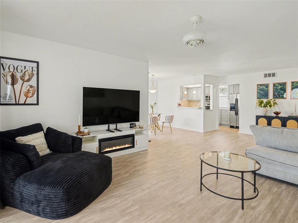 A living room with light wood floors, a black corduroy chair, and a fireplace console — 5174 MARSH FIELD LANE UNIT 86, SARASOTA, FL