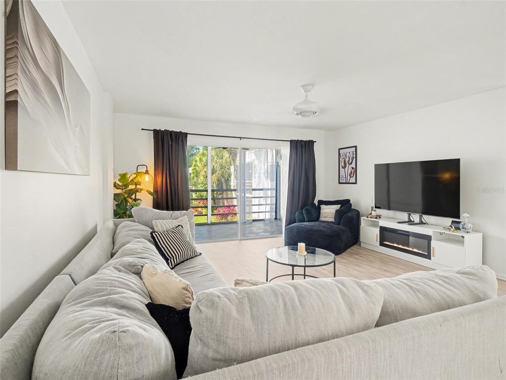 A living room features a large sectional sofa, a television on a console, and sliding doors — 5174 MARSH FIELD LANE UNIT 86, SARASOTA, FL