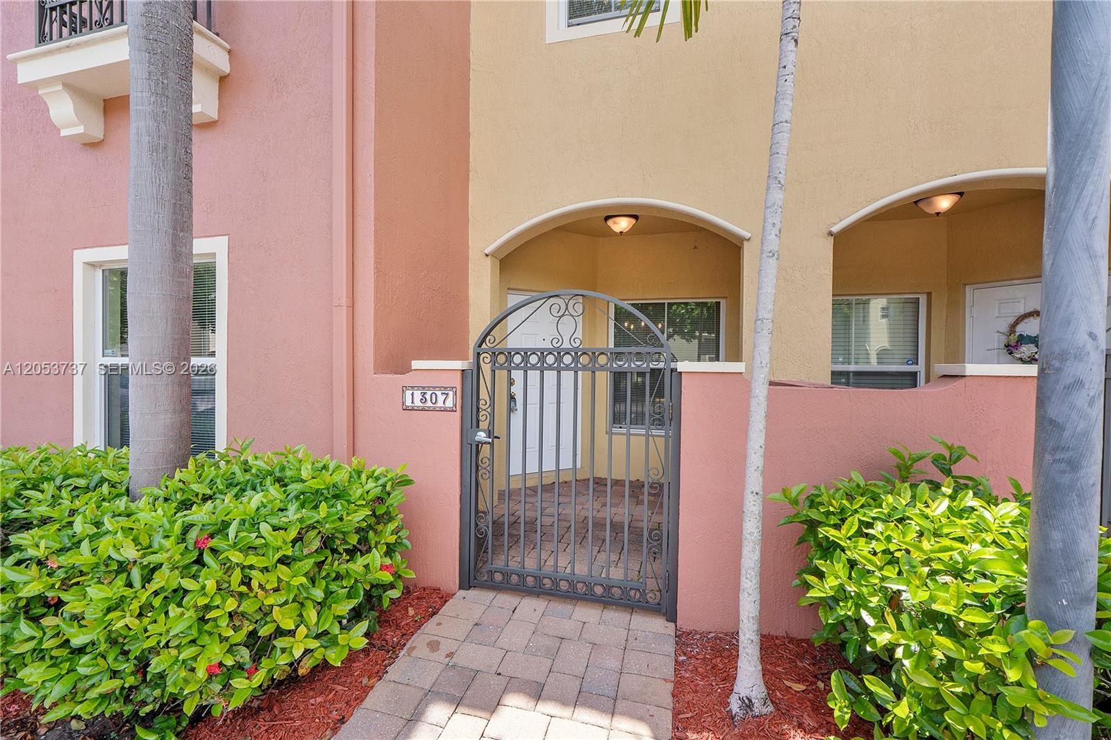 A gated brick walkway leads to the entrance of a two-story stucco townhouse — 2851 W Prospect Rd # 1307, Tamarac FL 33309, TAMARAC, FL