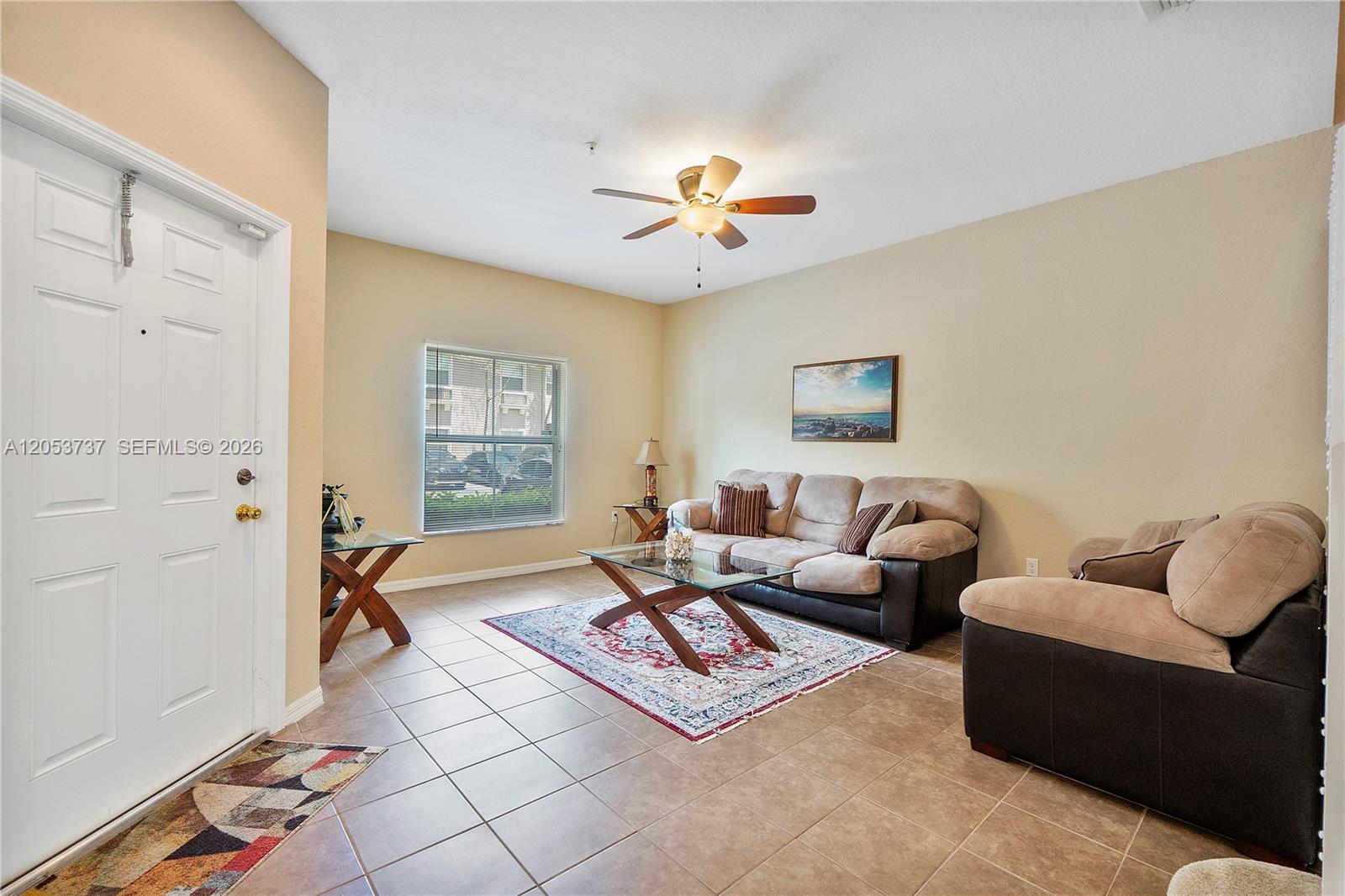 A living room features beige walls, tile flooring, a ceiling fan, and two sofas — 2851 W Prospect Rd # 1307, Tamarac FL 33309, TAMARAC, FL