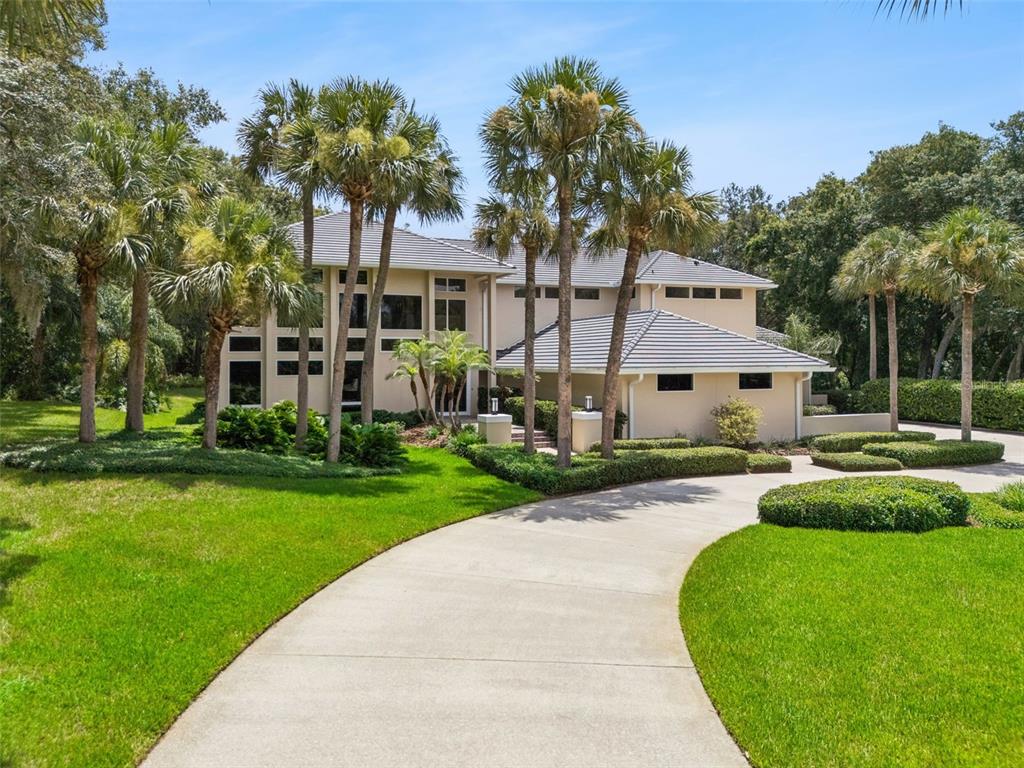 A two-story house with a concrete driveway, palm trees, and manicured landscaping — 632 E CLUB CIRCLE, LONGWOOD, FL