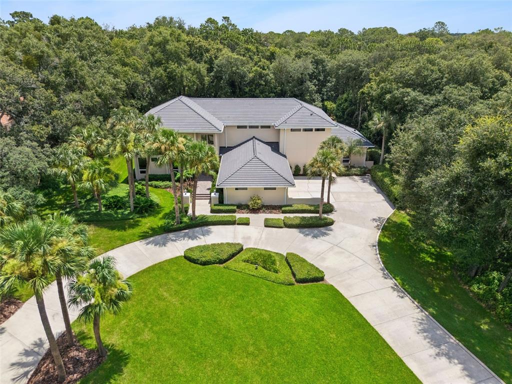 An aerial view shows a two-story house with a tile roof, circular driveway, and landscaping — 632 E CLUB CIRCLE, LONGWOOD, FL