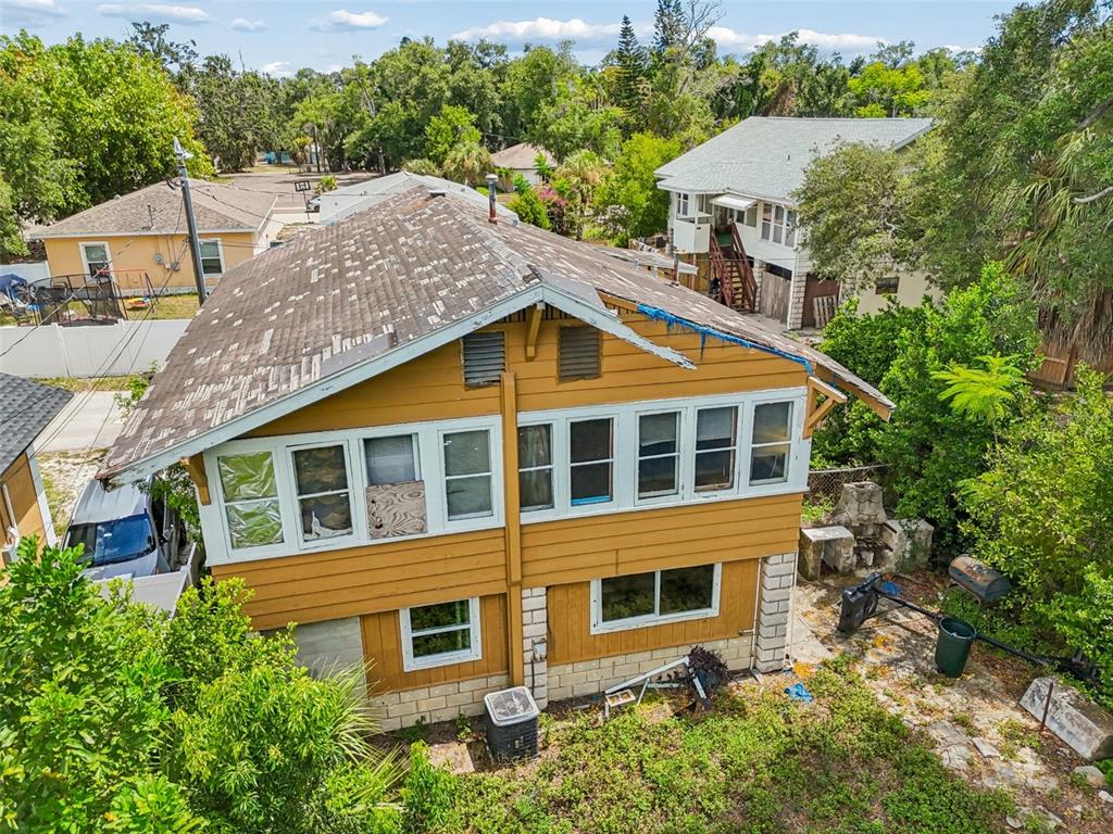 An aerial view of a two-story yellow house with a damaged roof and boarded windows — 2210 20TH AVENUE S, ST PETERSBURG, FL